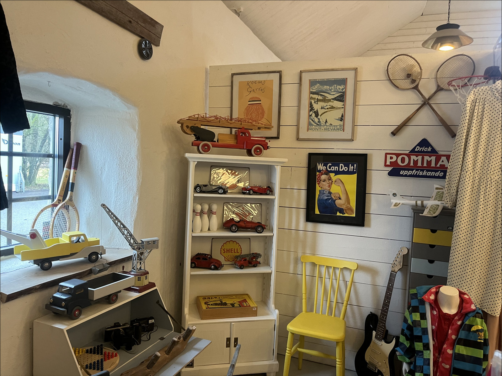 Hörna i butiken med leksaksbilar, gamla skyltar och tennisracketar